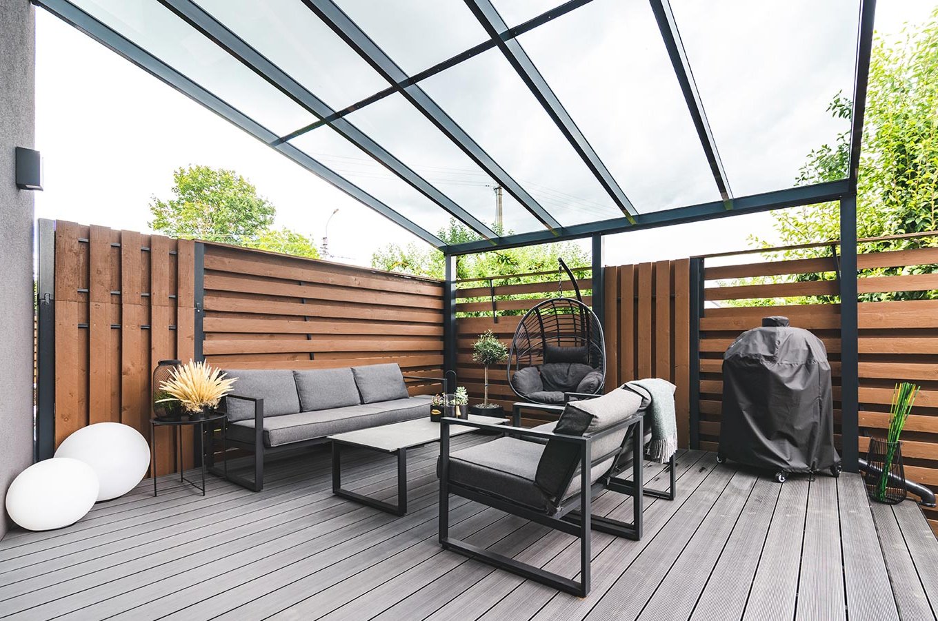 Terrassenüberdachungen aus Aluminium bei Gschwander Eine gemütliche Terrasse mit Möbeln, Zaun und einer Terrassenüberdachung aus Aluminium
